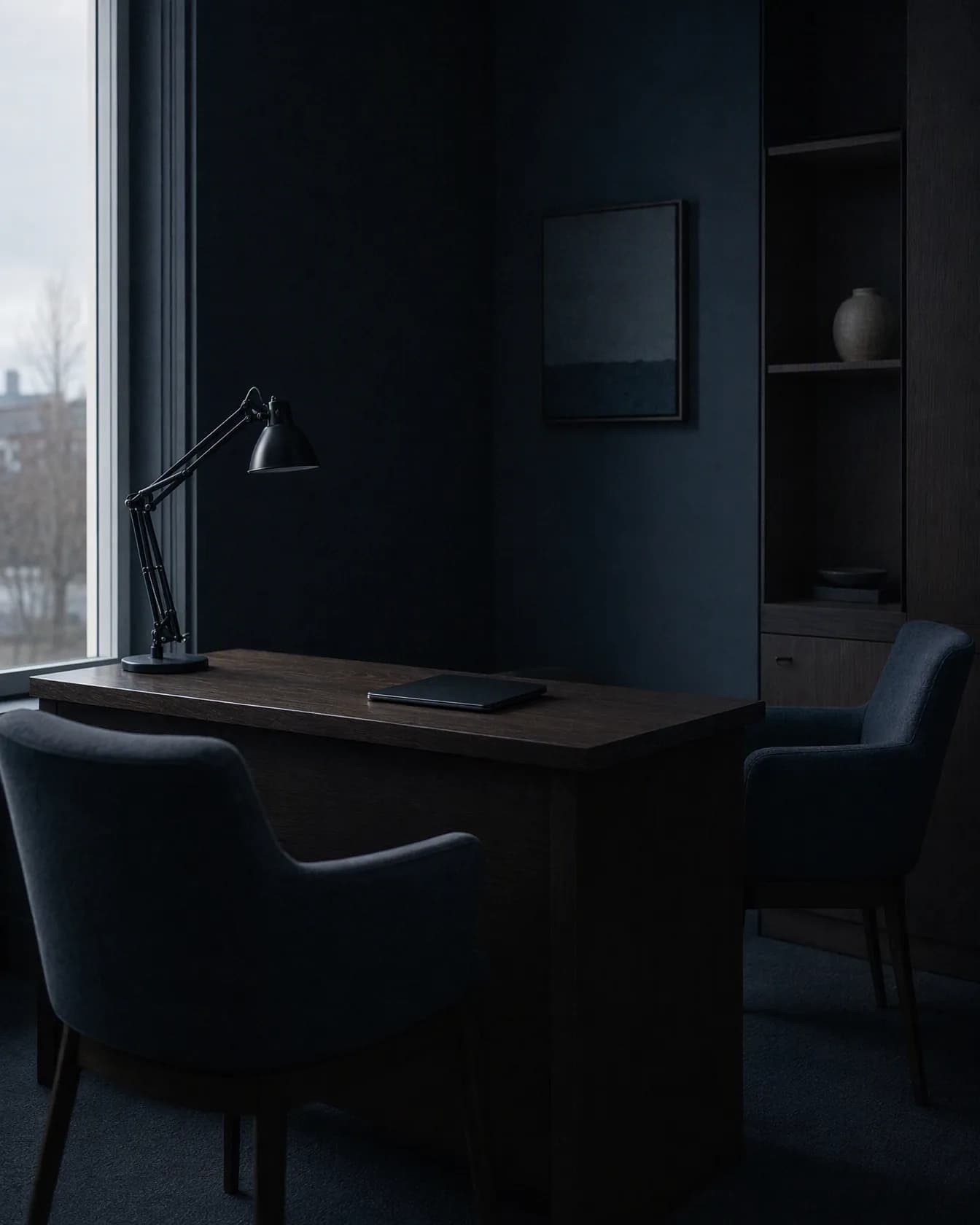A consultation room with two chairs facing each other across an oak desk, daylight from a tall window